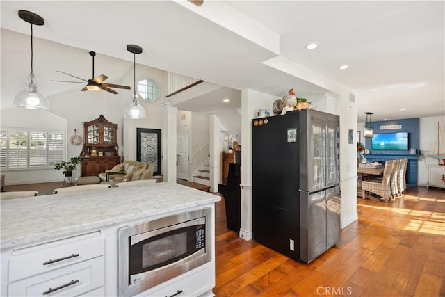 kitchen with light wood-type flooring, appliances with stainless steel finishes, white cabinets, and pendant lighting