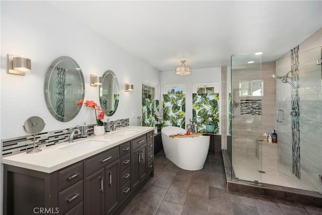 full bath featuring double vanity, a freestanding tub, a sink, and a shower stall