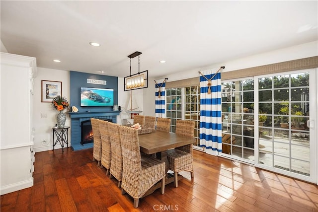 dining space with a lit fireplace, hardwood / wood-style floors, a healthy amount of sunlight, and recessed lighting