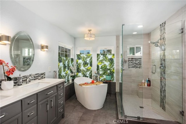 full bath with double vanity, tile patterned floors, a freestanding tub, a shower stall, and a sink