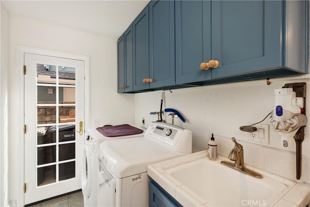 clothes washing area featuring washing machine and dryer, a sink, and cabinet space