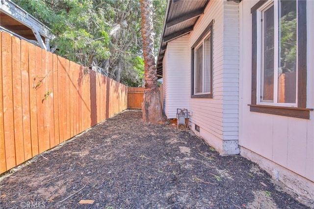 view of side of home with crawl space and fence