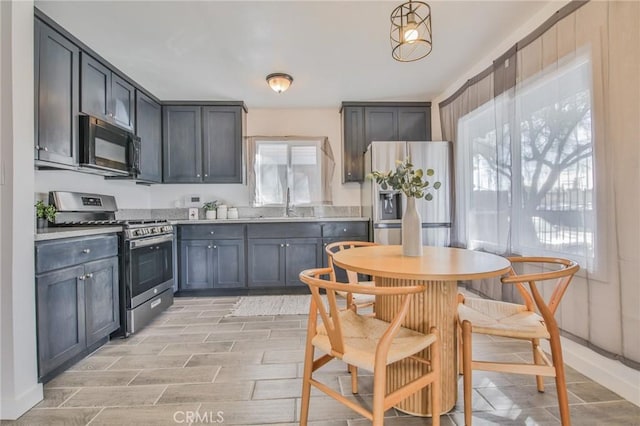 kitchen with light countertops, appliances with stainless steel finishes, a sink, and a healthy amount of sunlight