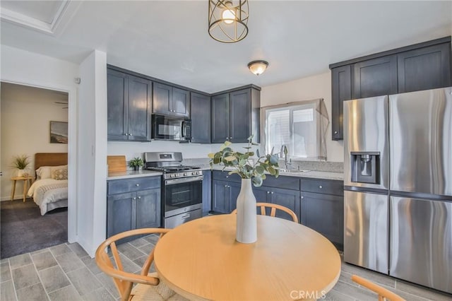 kitchen featuring appliances with stainless steel finishes, light countertops, a sink, and baseboards