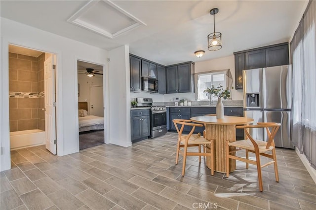 kitchen with stainless steel appliances, a breakfast bar, light countertops, and decorative light fixtures