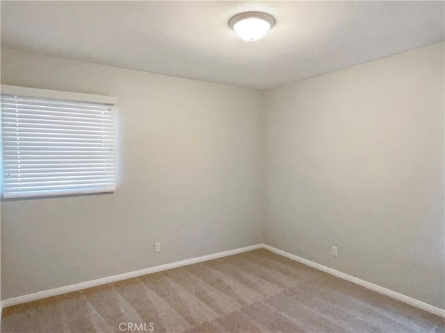 spare room with light colored carpet and baseboards