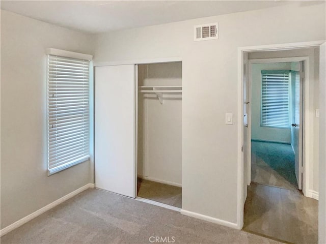 unfurnished bedroom with carpet floors, a closet, visible vents, and baseboards