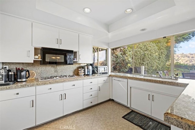 kitchen with white appliances, a raised ceiling, decorative backsplash, and light tile patterned floors