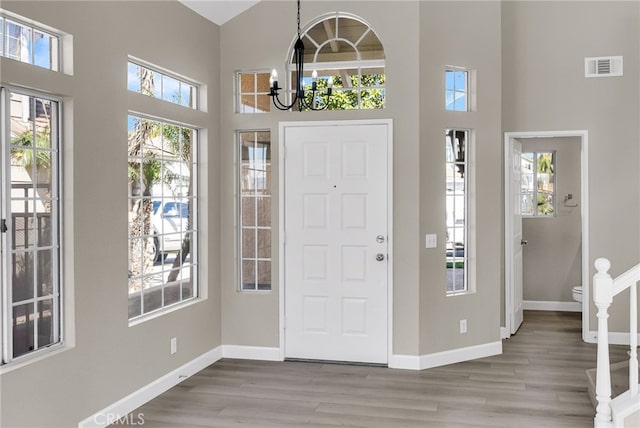 entryway featuring a high ceiling, wood finished floors, visible vents, and baseboards