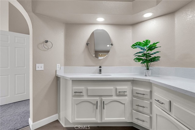 bathroom featuring recessed lighting, a textured wall, vanity, and baseboards