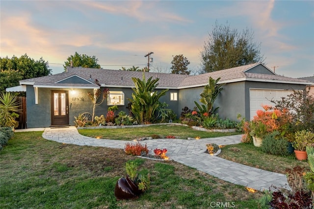 single story home with a garage, stucco siding, french doors, and a front yard