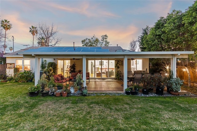 back of property with fence, a yard, stucco siding, ceiling fan, and an outdoor hangout area