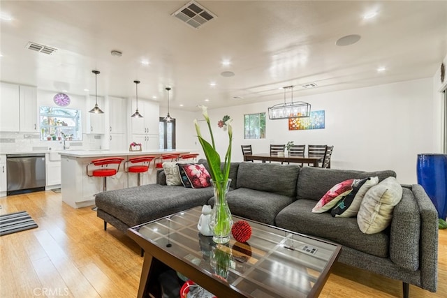 living room featuring light wood-type flooring, visible vents, and recessed lighting