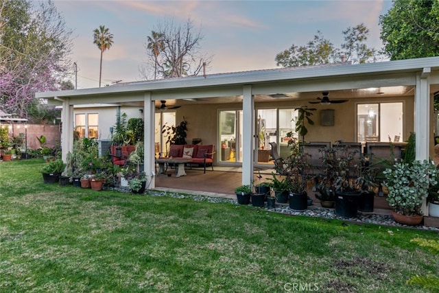 back of property featuring stucco siding, a lawn, a patio, outdoor lounge area, and ceiling fan