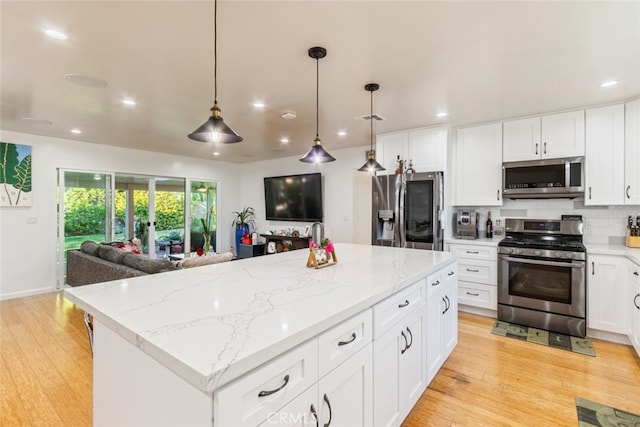 kitchen with light wood-type flooring, appliances with stainless steel finishes, open floor plan, and white cabinets