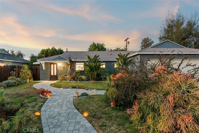 ranch-style home featuring stucco siding, a front lawn, and fence