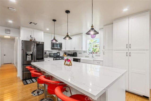 kitchen with visible vents, a sink, light wood-style floors, appliances with stainless steel finishes, and white cabinetry