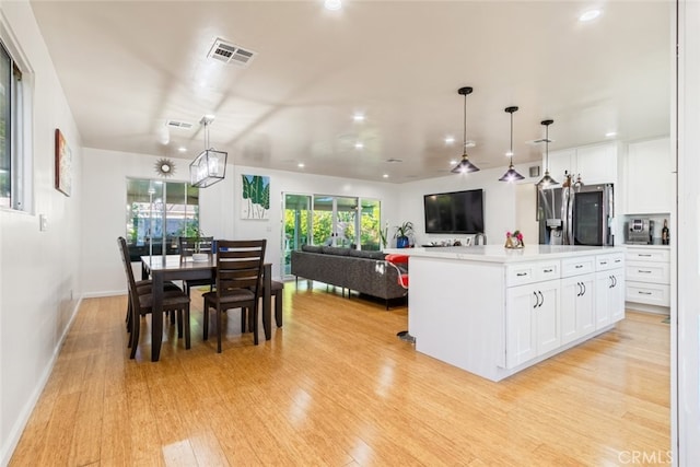 kitchen with visible vents, stainless steel fridge, white cabinetry, and light wood finished floors