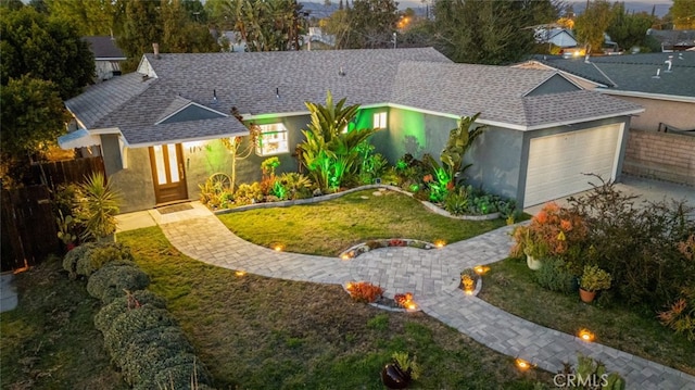 ranch-style house with driveway, a garage, roof with shingles, and stucco siding