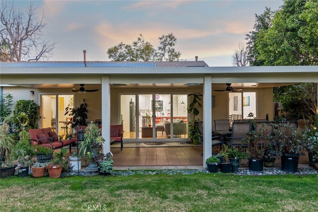 back of property with a patio area, a yard, a ceiling fan, and stucco siding