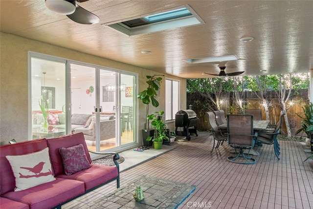 sunroom with a wealth of natural light, a skylight, and ceiling fan