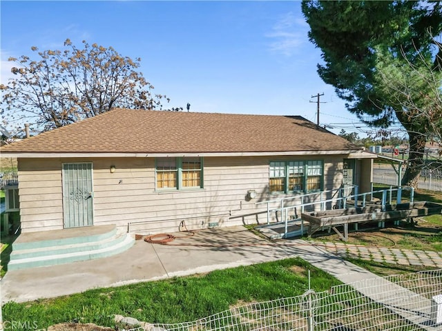 rear view of house with a patio and roof with shingles