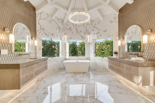 bathroom with a sink, a freestanding tub, two vanities, and marble finish floor