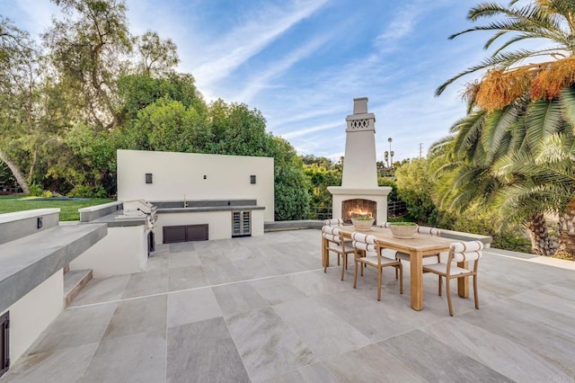 view of patio / terrace with an outdoor kitchen, grilling area, and a lit fireplace