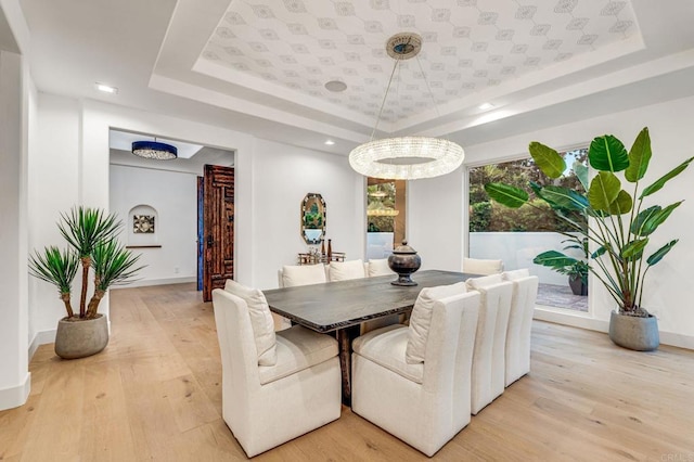 dining room featuring light wood finished floors and a tray ceiling