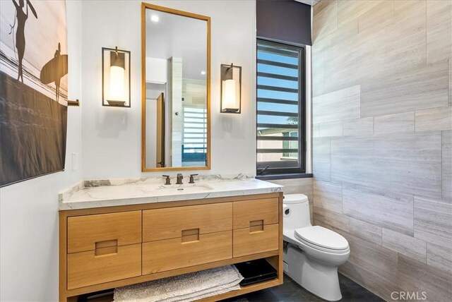 bathroom with vanity, toilet, and tile walls