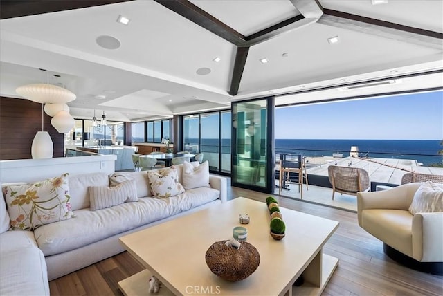 living room featuring beamed ceiling, a water view, wood finished floors, and floor to ceiling windows