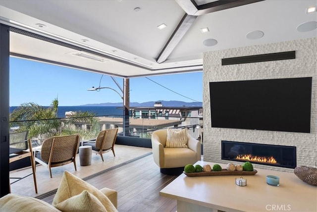 living area featuring a wealth of natural light, a fireplace, lofted ceiling with beams, and wood finished floors