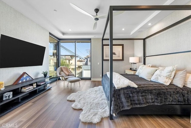 bedroom featuring access to outside, a tray ceiling, wood finished floors, and recessed lighting