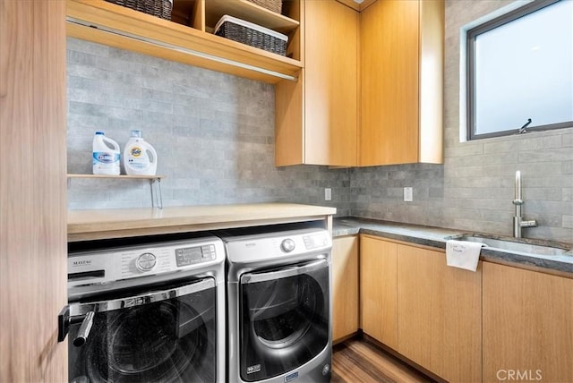 laundry room featuring cabinet space, washer and clothes dryer, a sink, and wood finished floors