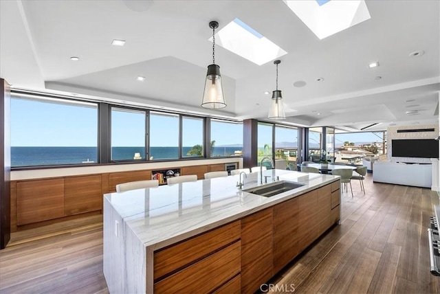 kitchen featuring brown cabinets, dark wood finished floors, open floor plan, a sink, and modern cabinets