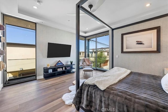 bedroom with a wall of windows, recessed lighting, wood finished floors, and access to exterior