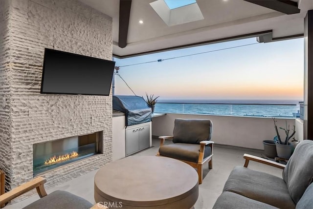 living room with a skylight, a glass covered fireplace, and recessed lighting