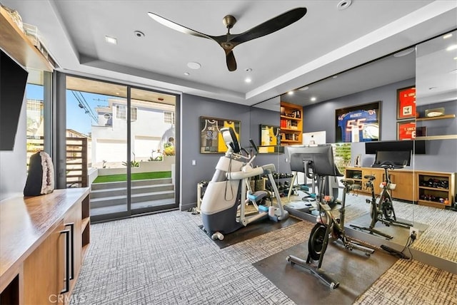 exercise area featuring ceiling fan, carpet floors, a tray ceiling, and recessed lighting