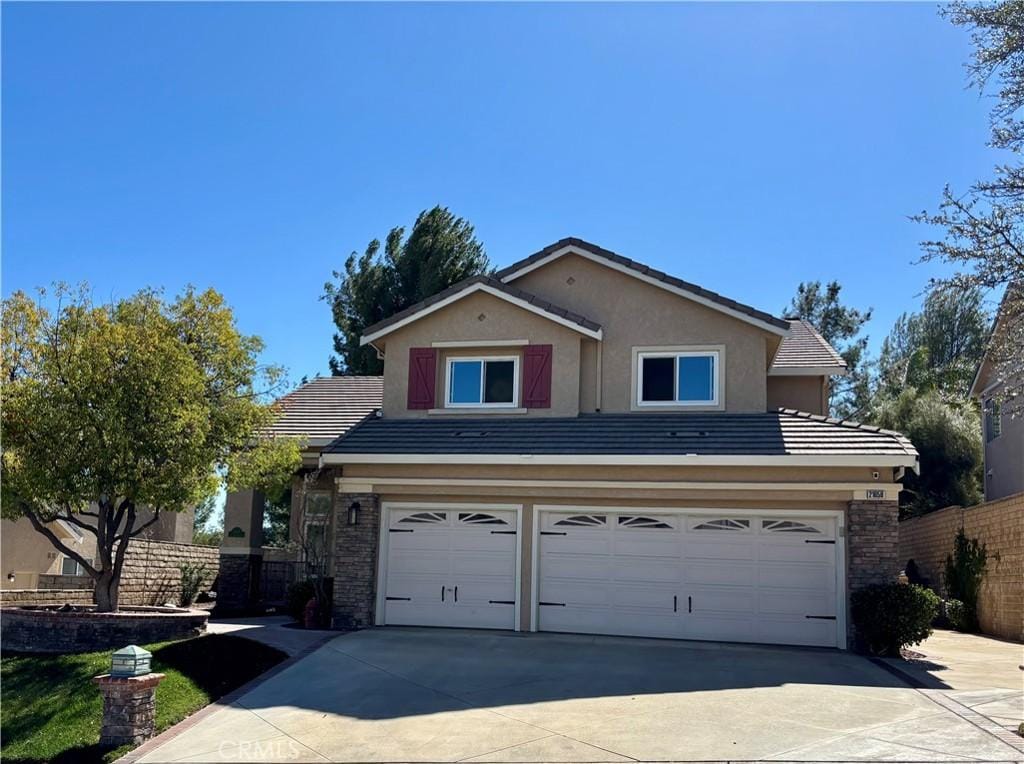 traditional-style house with stucco siding, fence, a garage, driveway, and a tiled roof