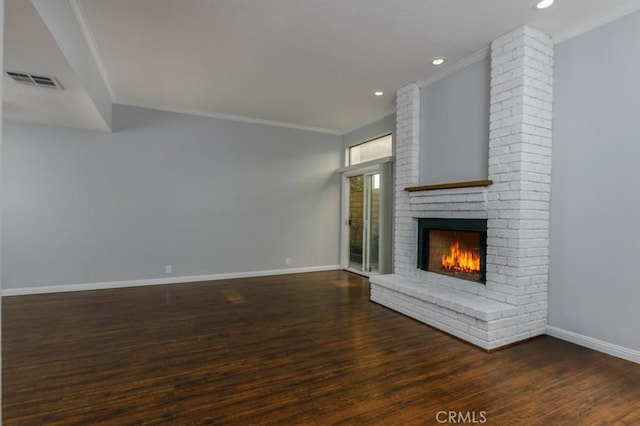 unfurnished living room with crown molding, visible vents, a brick fireplace, wood finished floors, and baseboards