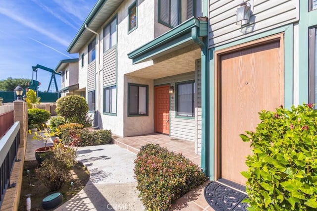 entrance to property featuring a patio area, fence, and stucco siding