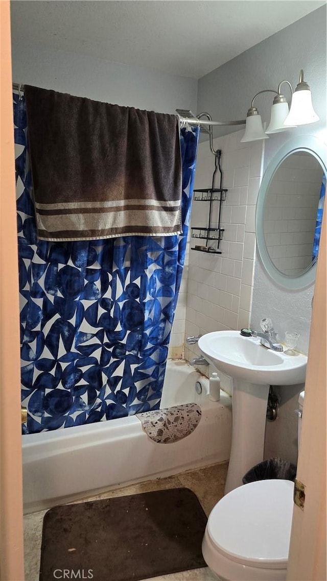 bathroom featuring a sink, shower / bath combo with shower curtain, and toilet