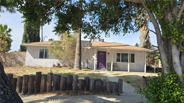 ranch-style house with a fenced front yard and stucco siding