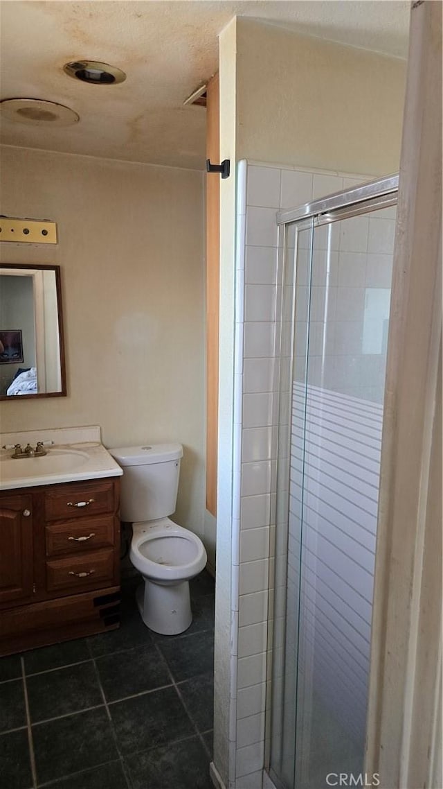 bathroom featuring toilet, a stall shower, tile patterned flooring, and vanity