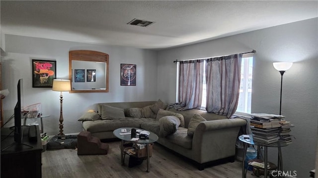 living area with visible vents and wood finished floors