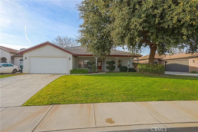 view of front of property with stucco siding, an attached garage, driveway, a tiled roof, and a front lawn