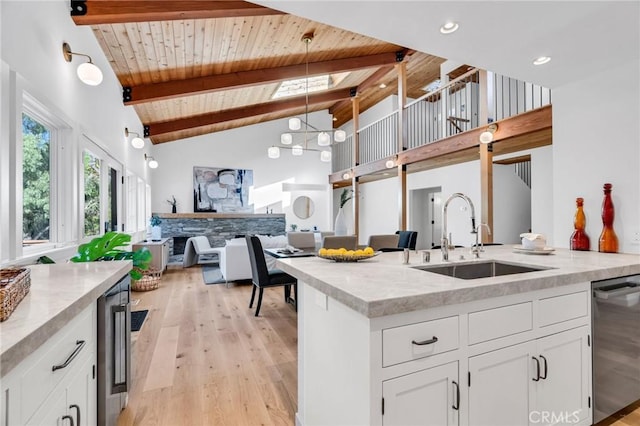 kitchen with beam ceiling, light wood-style floors, open floor plan, a sink, and dishwasher