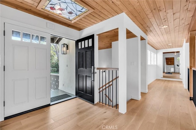 foyer featuring light wood-style flooring, wood ceiling, and baseboards