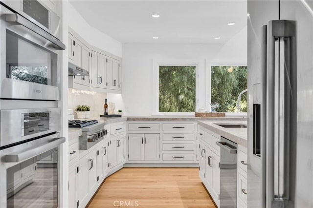 kitchen featuring stainless steel appliances, light countertops, under cabinet range hood, and white cabinetry