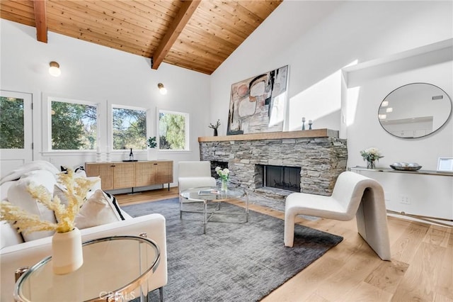 living area with wooden ceiling, wood finished floors, beam ceiling, and a stone fireplace